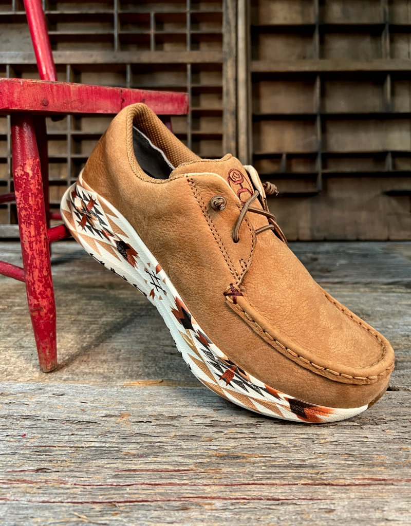 Brown leather shoe with aztec pattern sole on a wooden surface