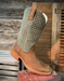 Brown cowboy boot with green patterned shaft on a wooden surface
