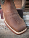Brown leather boot with a square toe on a wooden surface