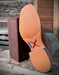 Close-up of a brown shoe sole with a wooden block on a rustic wooden surface.
