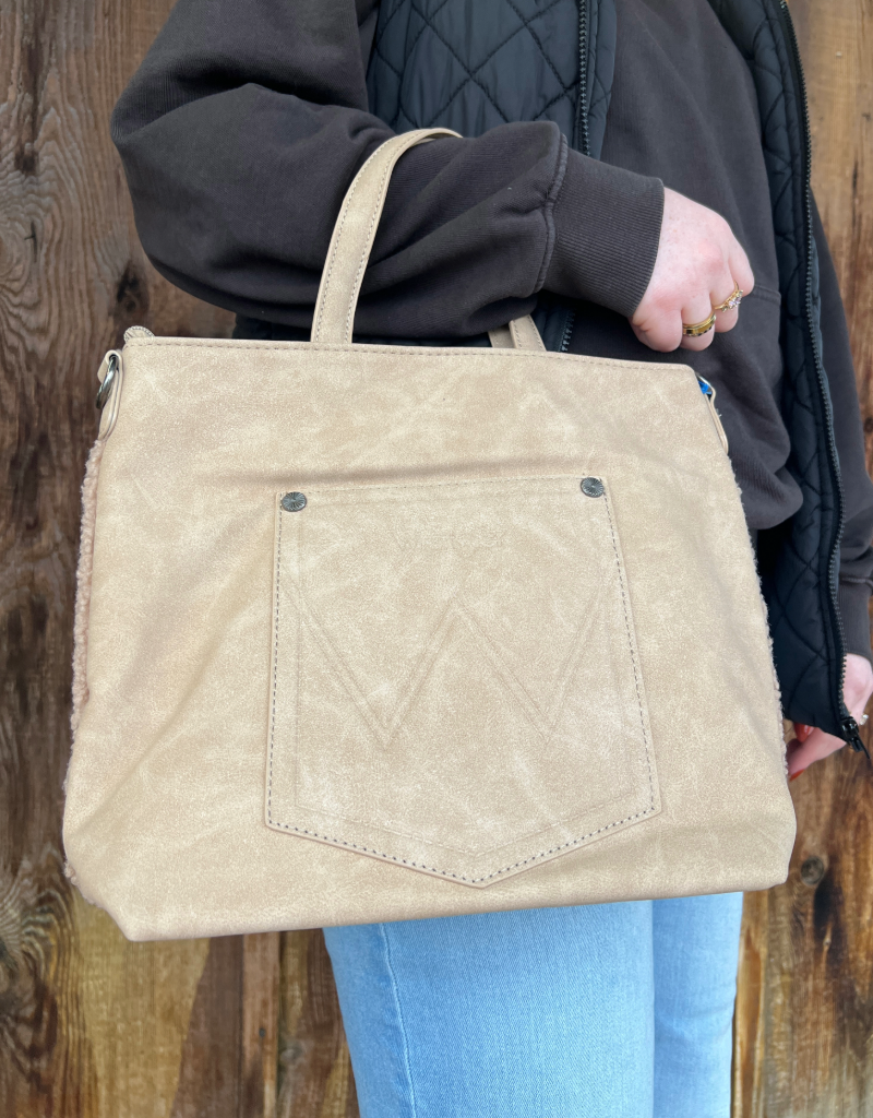 Beige handbag held by a person against a wooden background