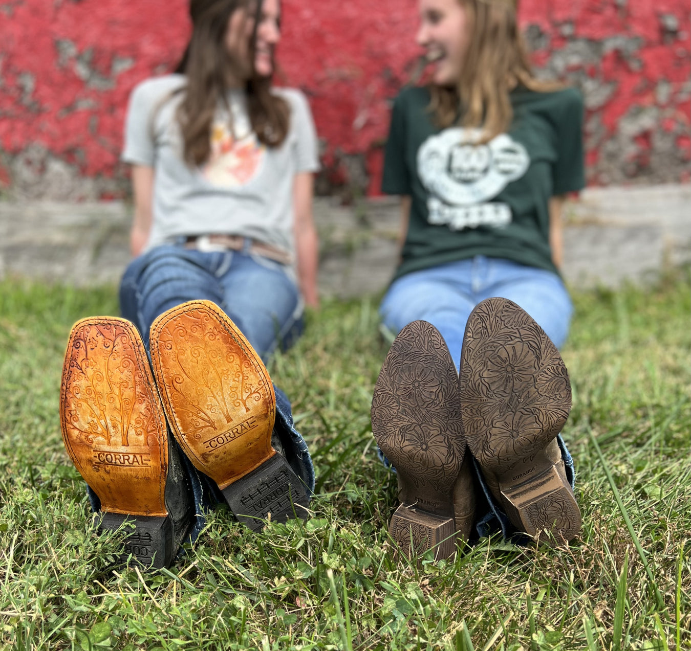 Two girls laying in the grass in cowgirl boots
