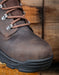 Brown leather boot with black sole on a wooden surface