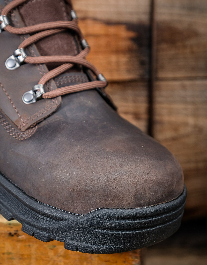 Brown leather boot with black sole on a wooden surface