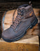 Brown leather boot with laces on a wooden barrel