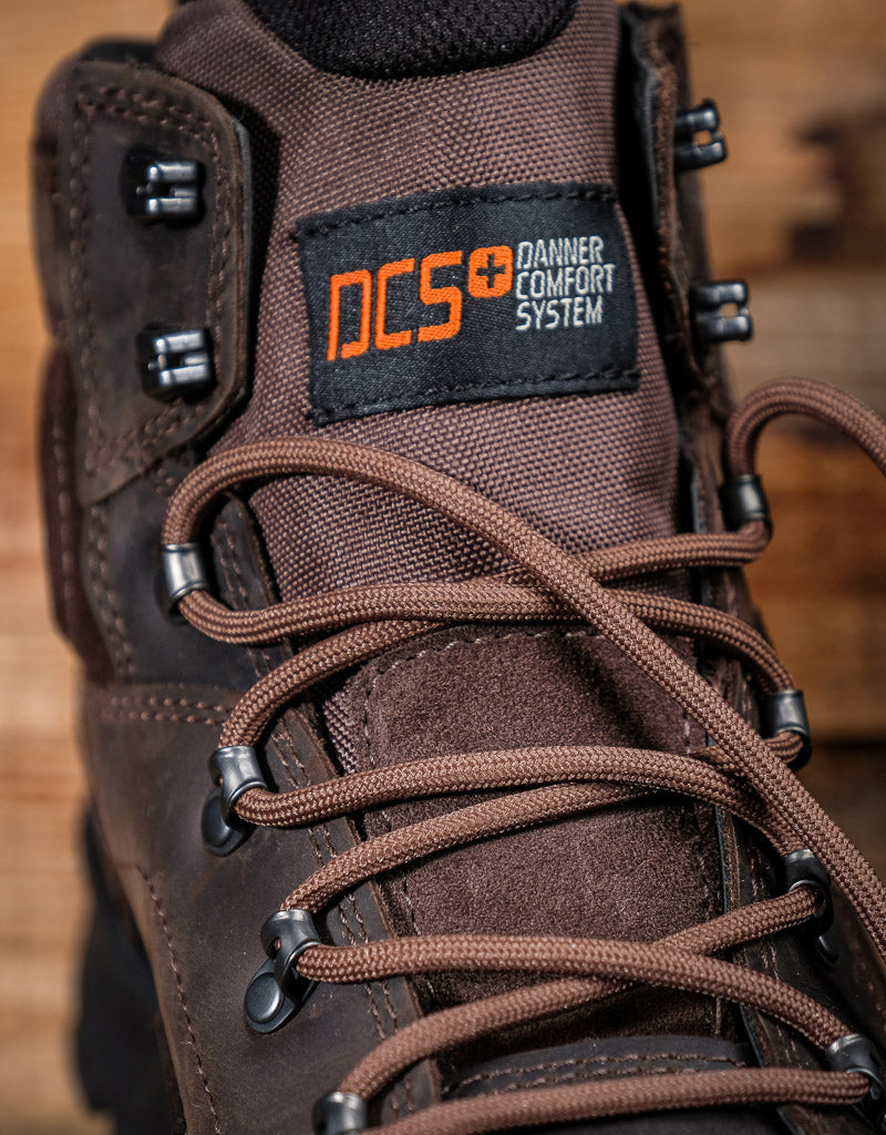Brown boot with DCS (Danner Comfort System) label on a wooden background