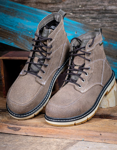 Pair of taupe leather boots with black laces on a wooden surface.