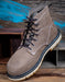 Brown suede boot with black laces on a wooden surface