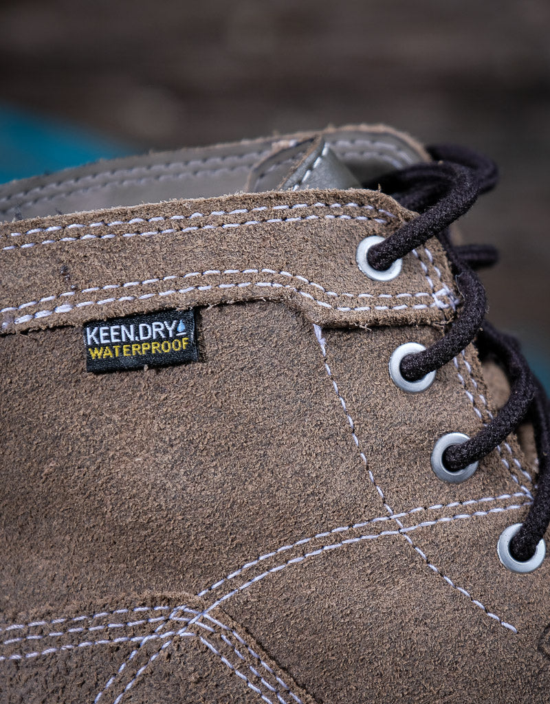 Close-up of a brown suede boot with a KEEN DRY WATERPROOF label on a blurred background