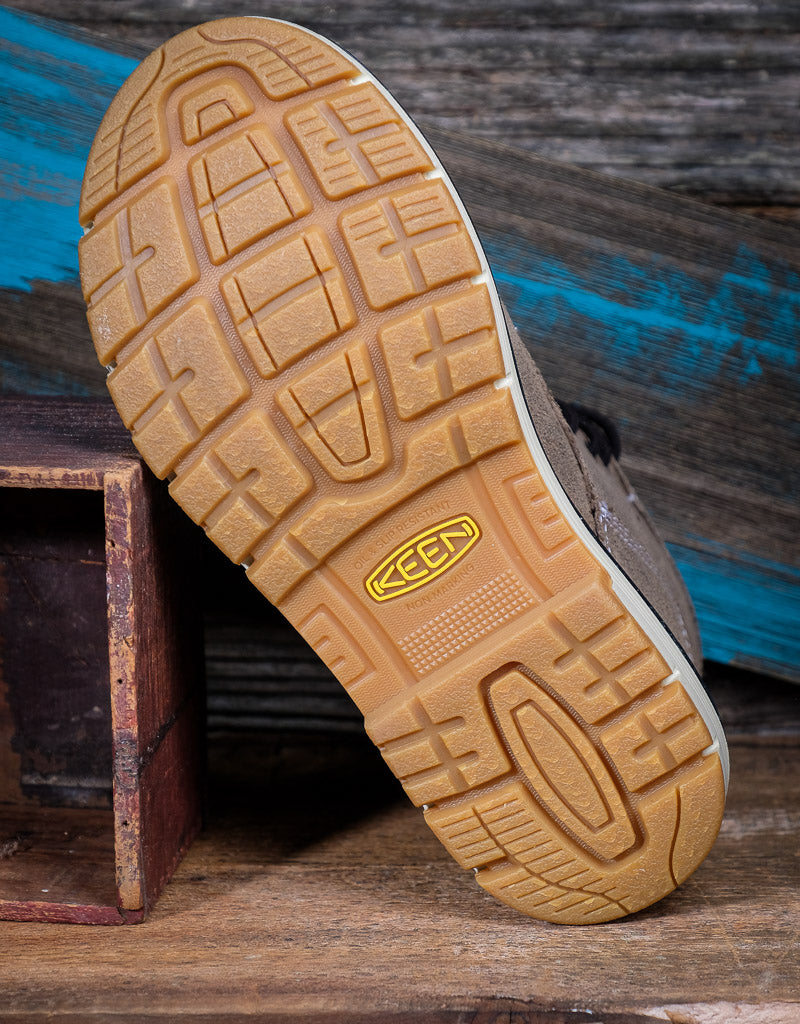 Close-up of a shoe sole with Keen logo on a wooden surface