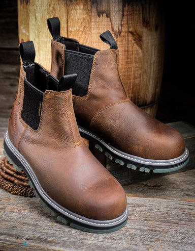 Pair of brown leather boots with black elastic sides on a wooden surface