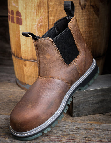 Brown leather boot with black sole on a wooden surface