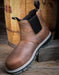 Brown leather boot with black sole on a wooden surface