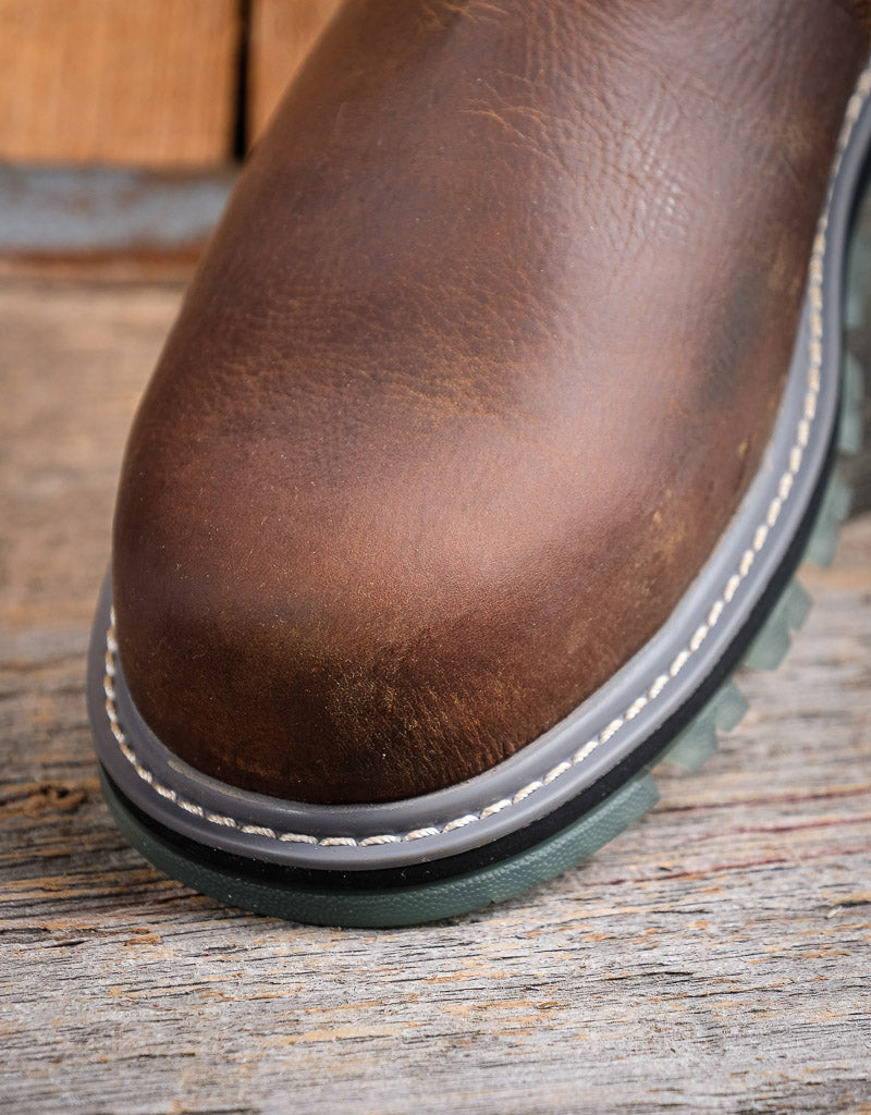 Close-up of a brown leather boot on a wooden surface