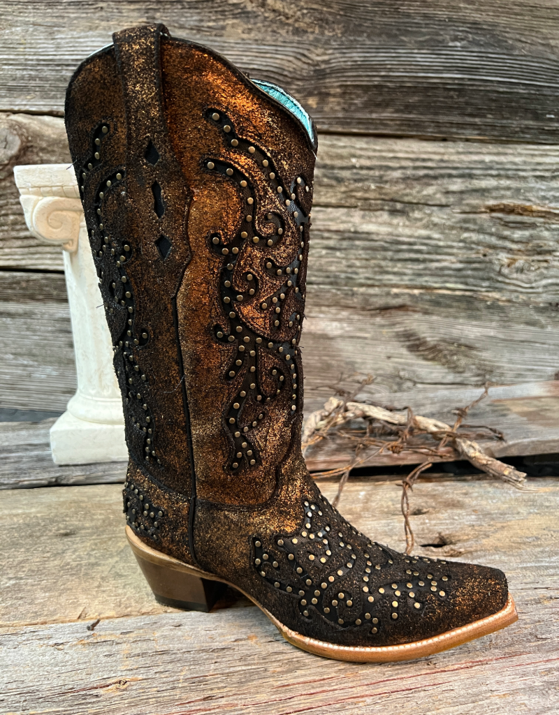 black and bronze cowboy boot with intricate studded detailing on a wooden surface.