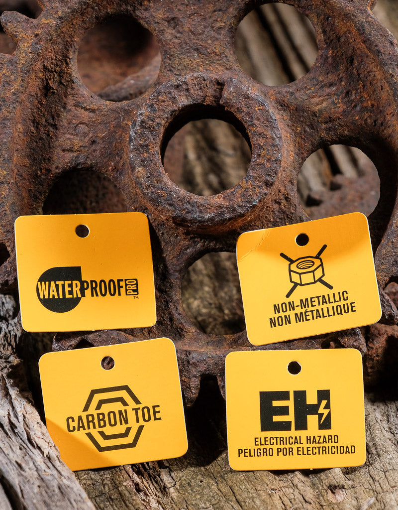 waterproof tag, non-metallic tag, carbon toe tag and EH protection tag laying against a rusty gear artistically