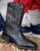 Profile view of Ariat My Country Black Flag boots sitting on top of pebbles with a patriotic banner behind