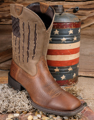 profile of Ariat My Country Cowboy boots with a red white and blue barrel behind